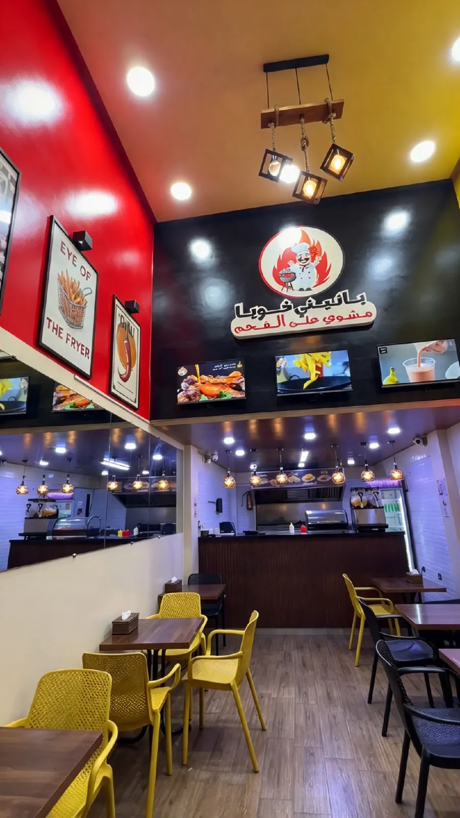 Intérieur de Panini Khouya : murs rouge et noir, enseigne du chef, tables en bois et chaises jaunes